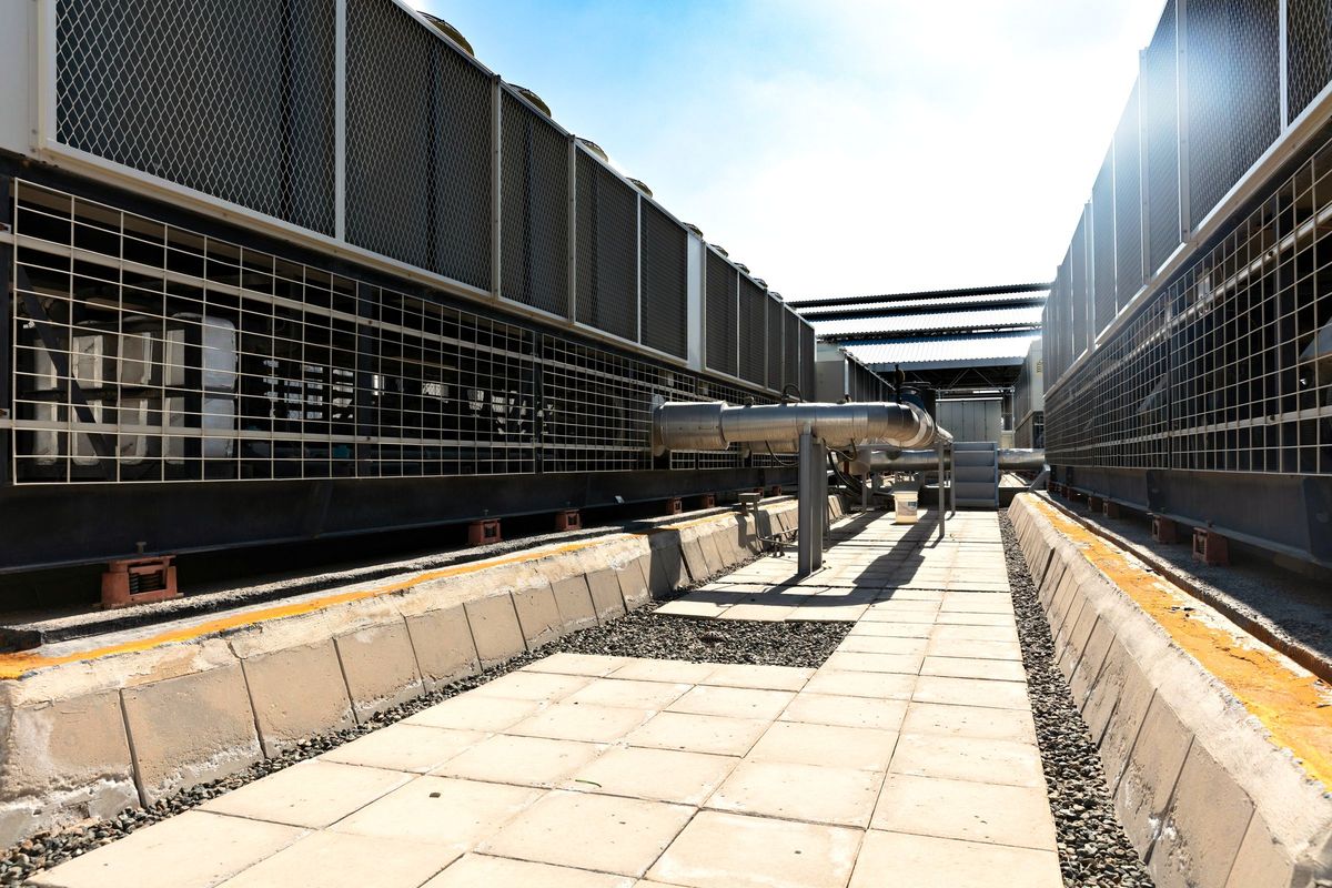 Rows of industrial air-cooled fan units along a walkway